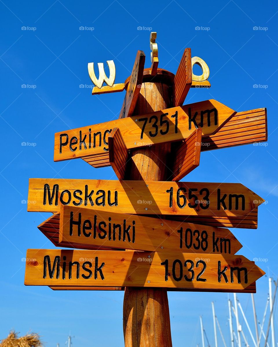 wooden sign showing distance from location to various cities