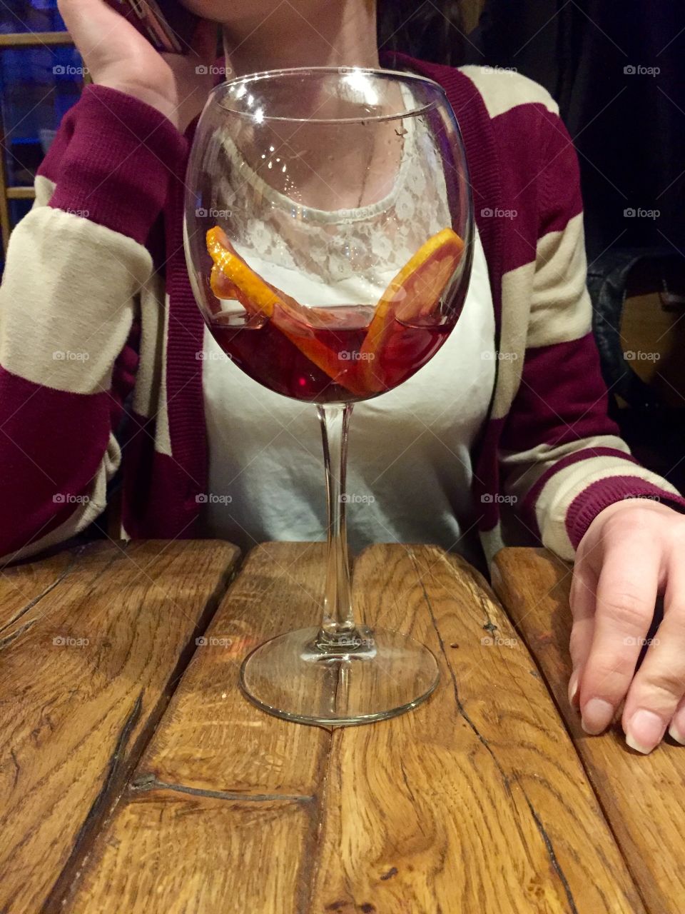 A glass of sangria with citrus on the table in front of a girl