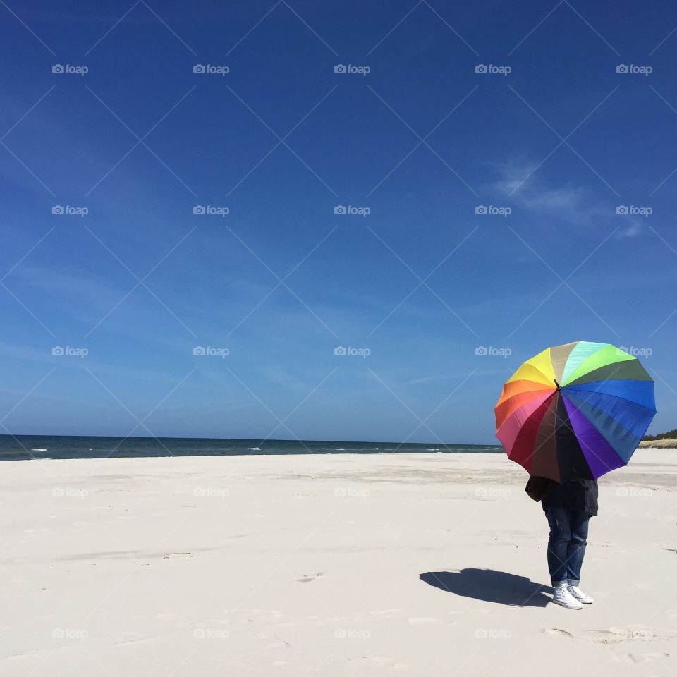 Person with colorful umbrella at sea