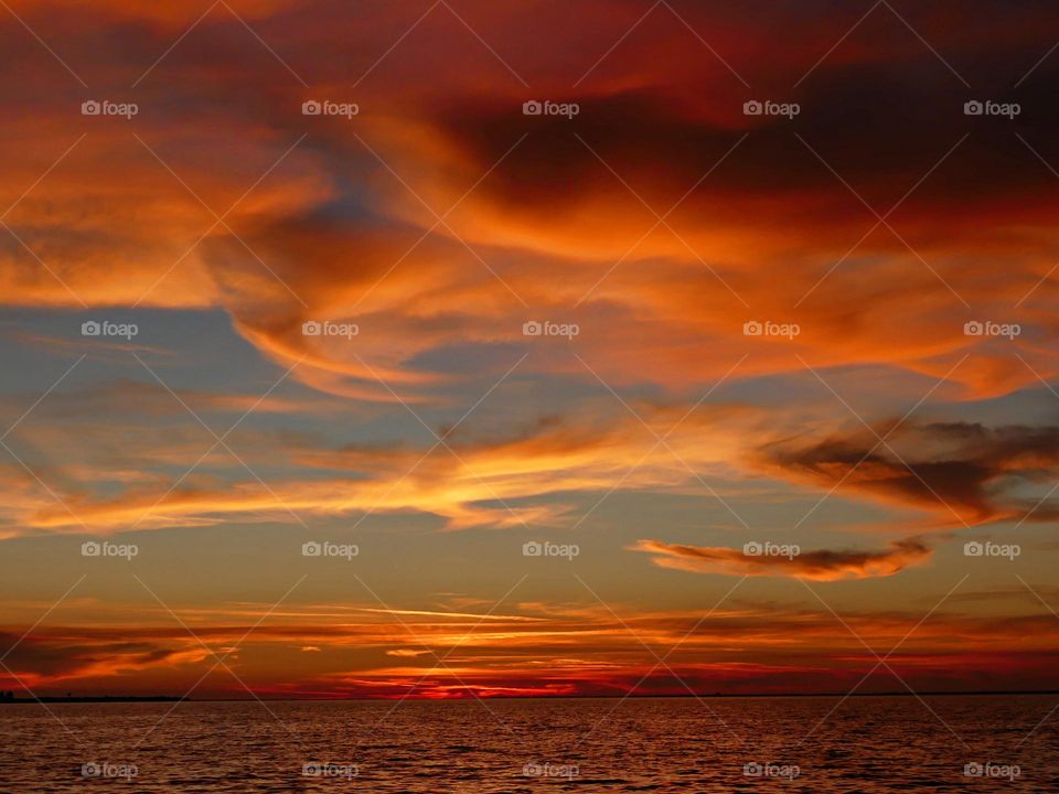 A Breathtaking descending sunset with picturesque peach colored Lenticular clouds over the Gulf of Mexico