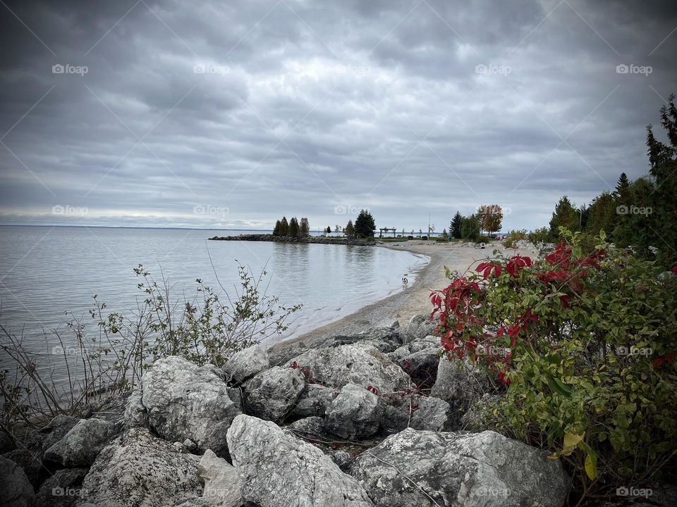 Collingwood Ontario sunset point , cloudy view of Georgian bay , beach , rocks and red flowers 