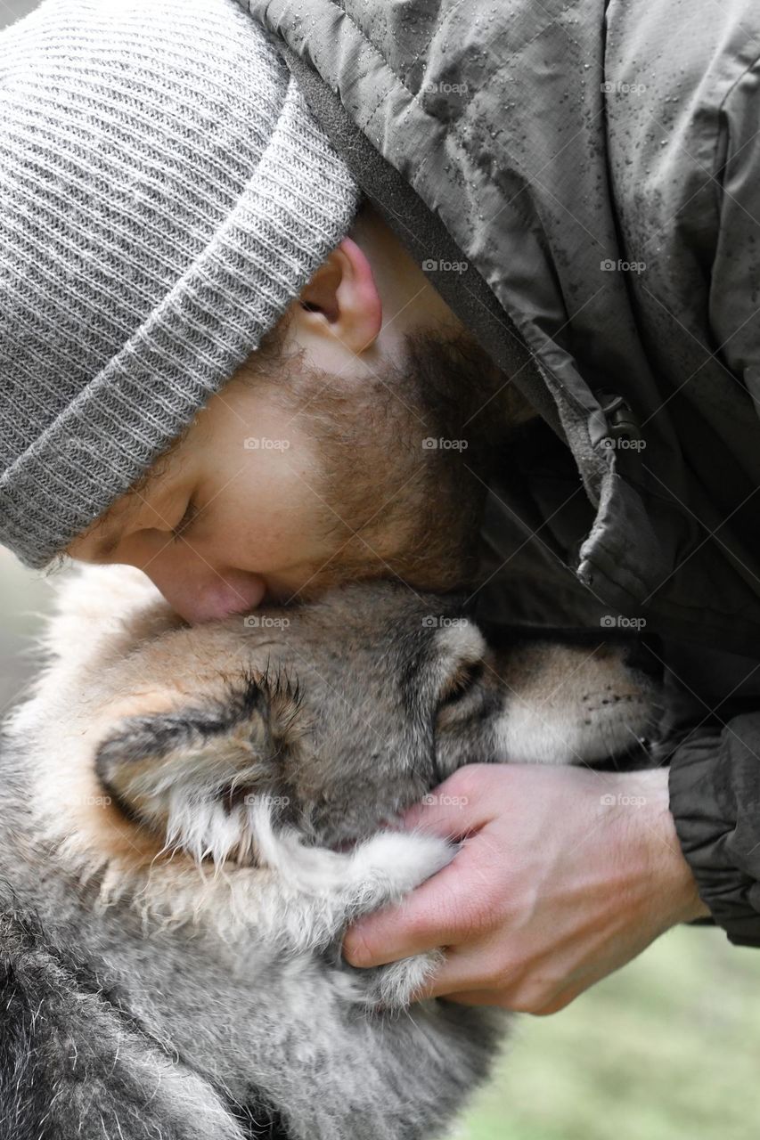 Portrait of a young man kissing his dog