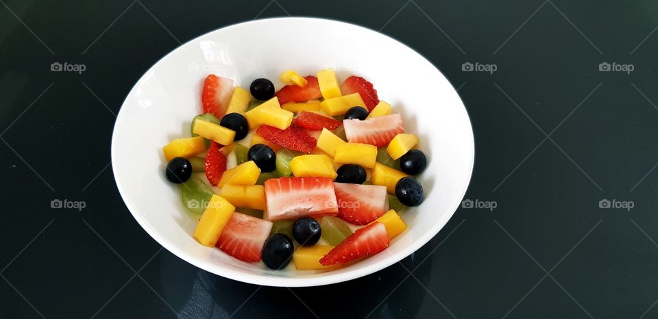 Healthy breakfast of yoghurt topped with fresh fruit and berries - colourful & tasty