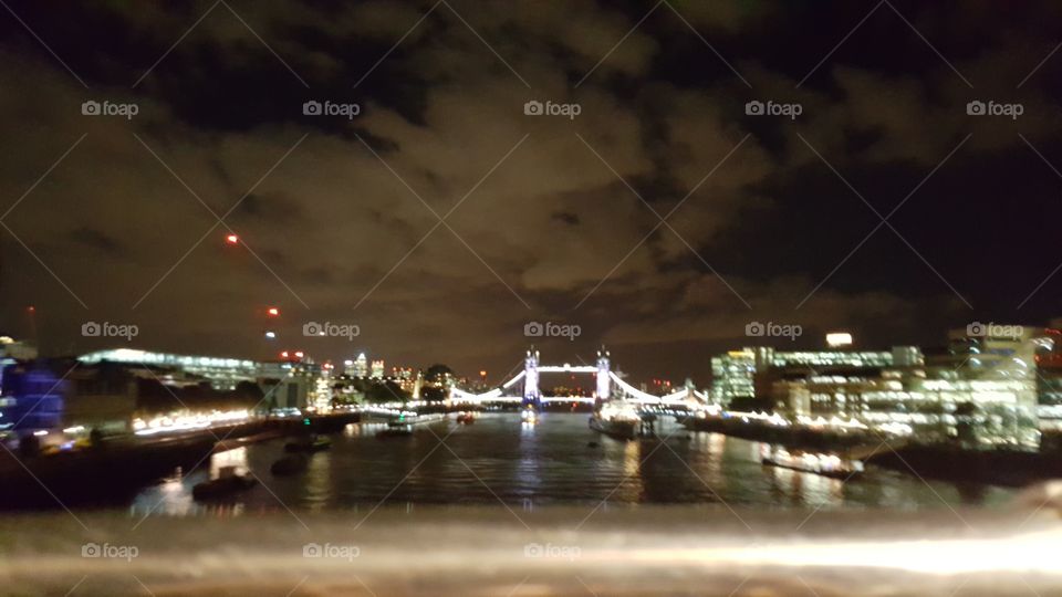 Tower Bridge lit up on a cloudy London night.