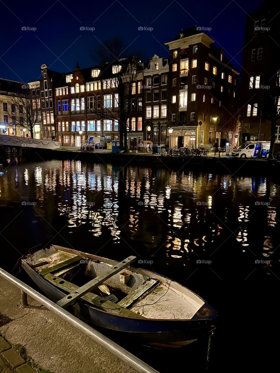 An old wooden boat is moored on a canal in Amsterdam. Its weathered hull reflects the atmosphere of the historic city, while the calm water adds charm and nostalgia