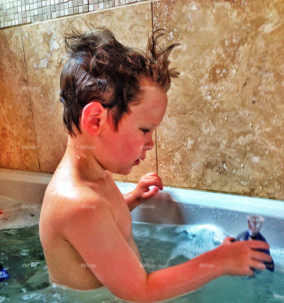 Young boy playing with toys in bath