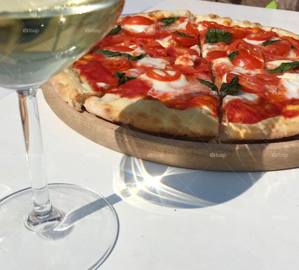 Pizza and a glass of wine. Margherita pizza and white wine. Perfect Italian lunch in the sun.