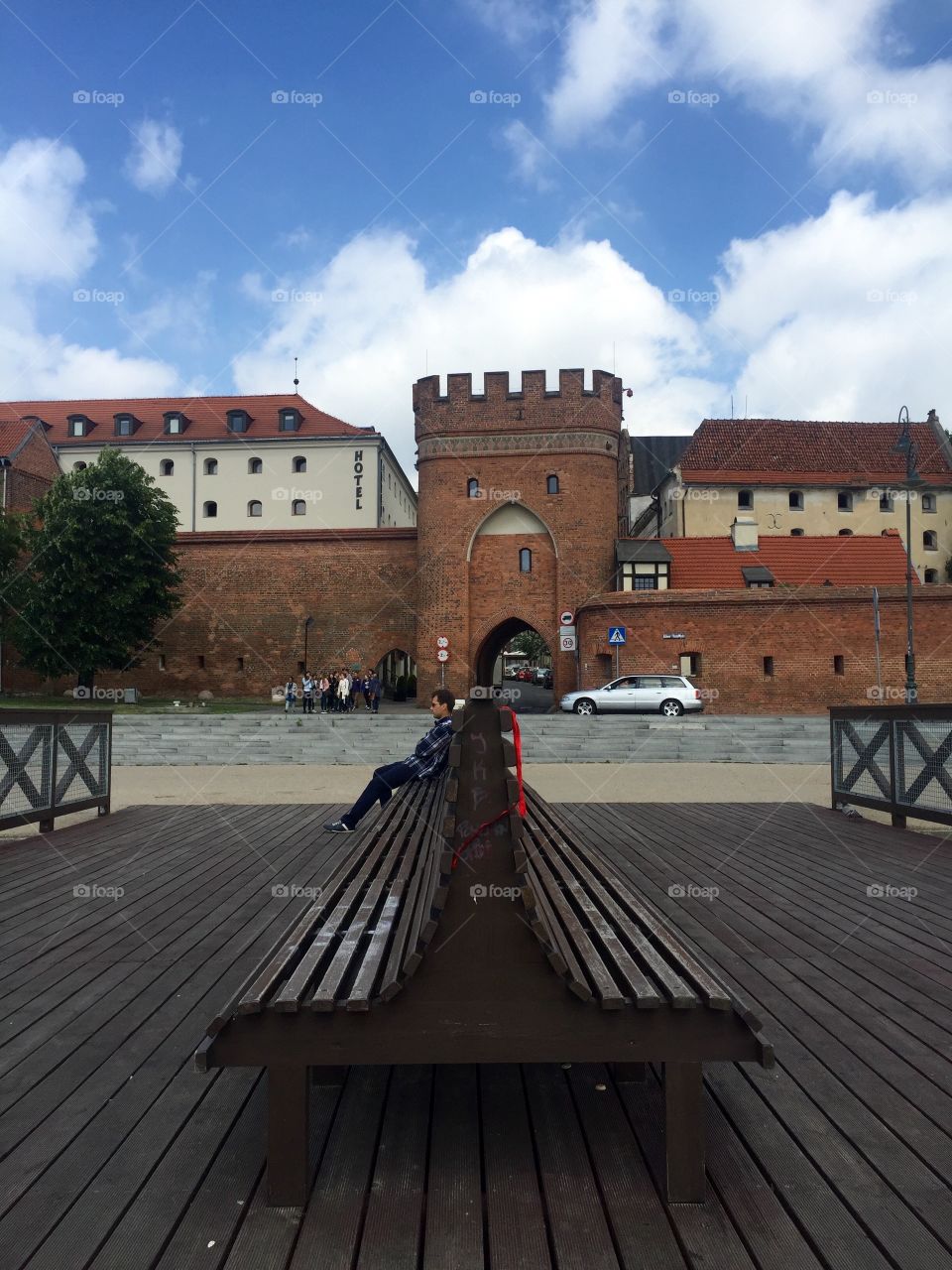 Lonely boy sitting on a bench across fortification in Torun