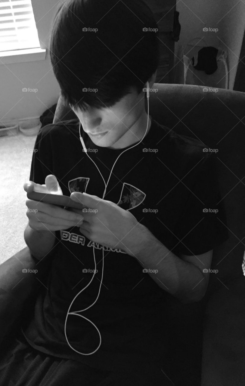 Teenage boy playing game on his iPod.