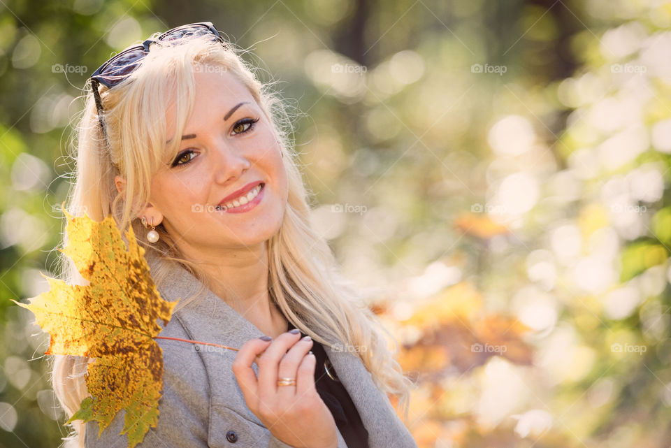 A young, blond and smilling woman portrait on a sunny autumn day.