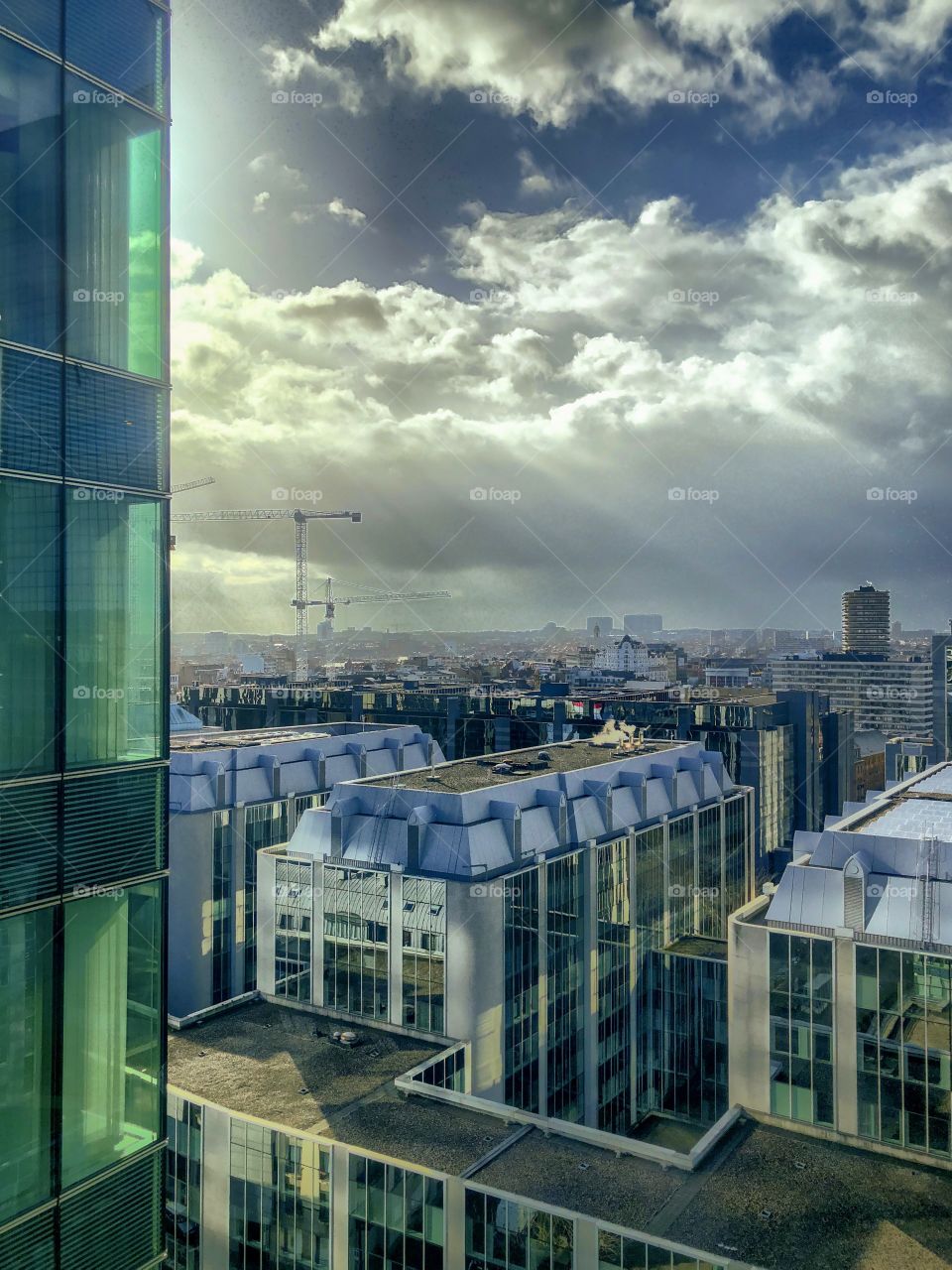 Rays of sun breaking through the thick clouds over the offices of the business district of the city of Brussels 