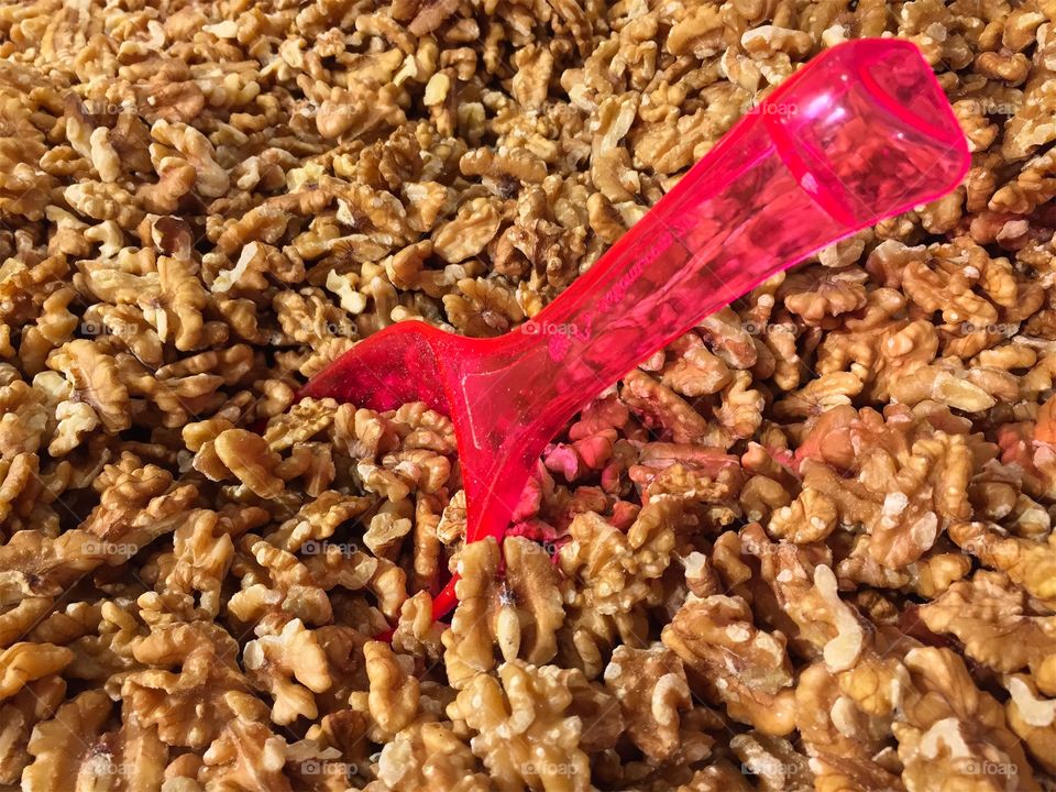 Close up of ripe peeled and dried walnut kernels for sale with a red spoon to scoop with. 