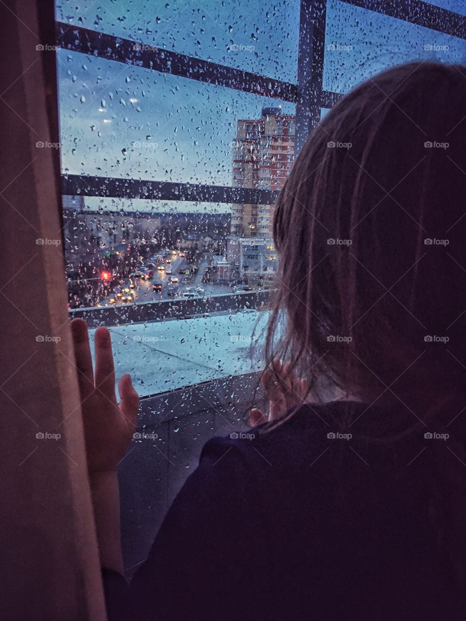 Girl looking through the window on rainy city 