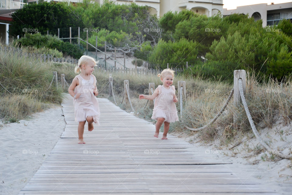 Young sister girls running and playing on their holiday in Majorca Spain.