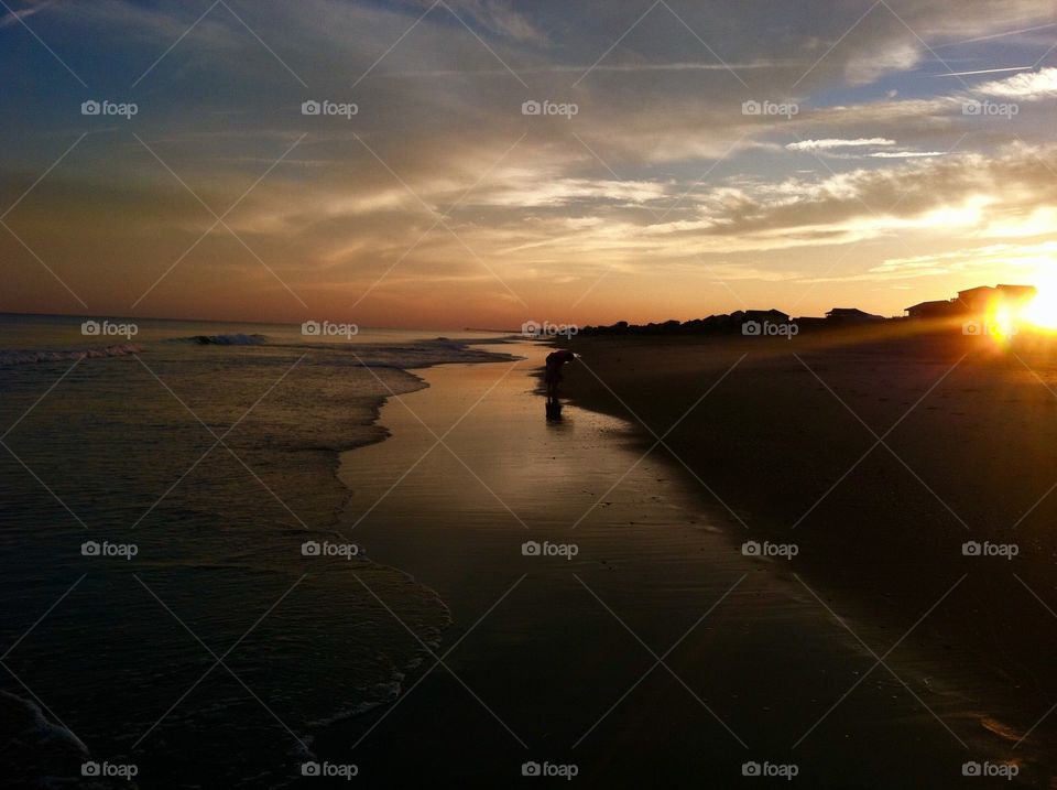 A mother and daughter stroll the beach at sunset at Emerald Isle in North Carolina. 