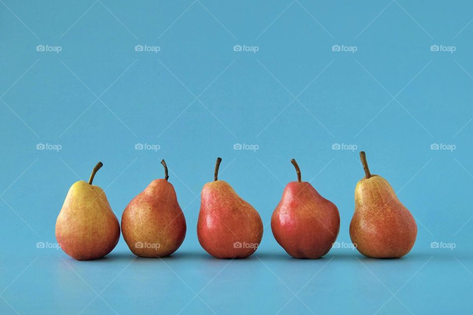 Close-Up of red-orange colored pears isolated on blue background. 
