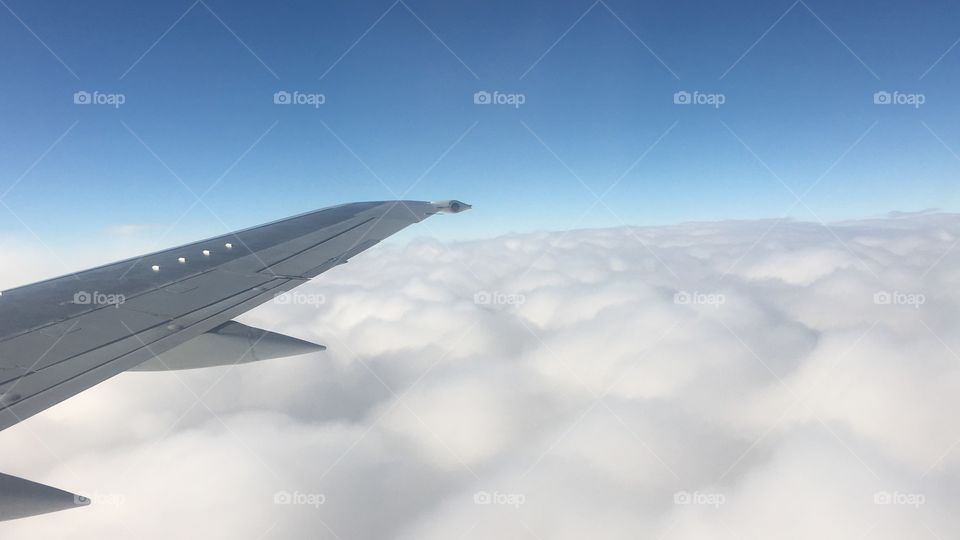 Wing of plane over clouds at sky