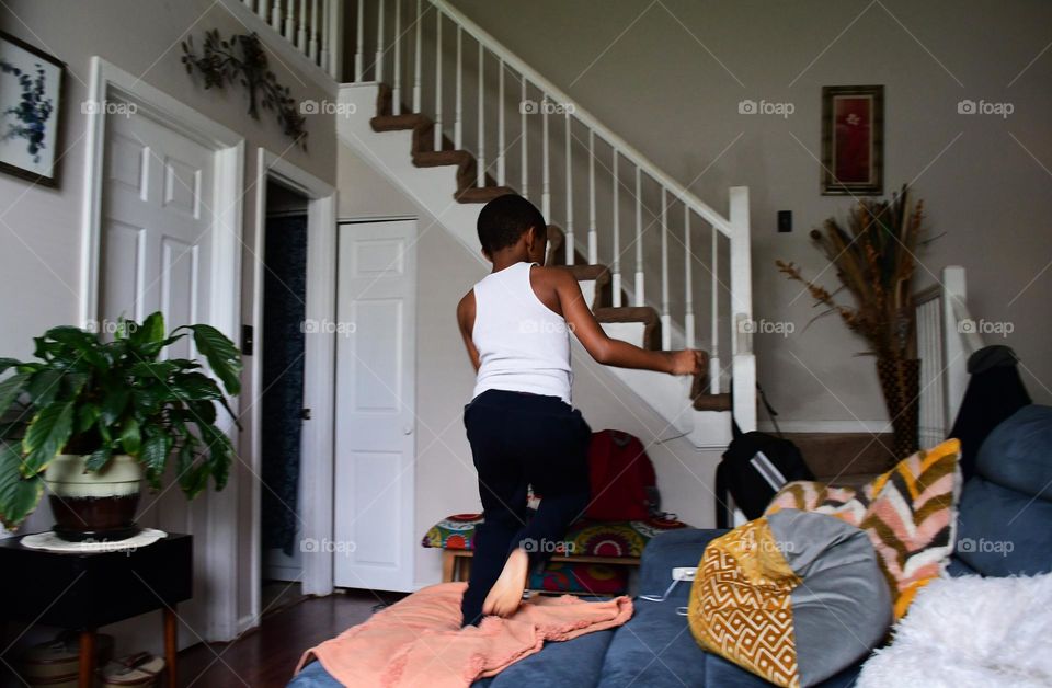 A kid full of playful energy is ignited with instant excitement as he hops of the living room couch.