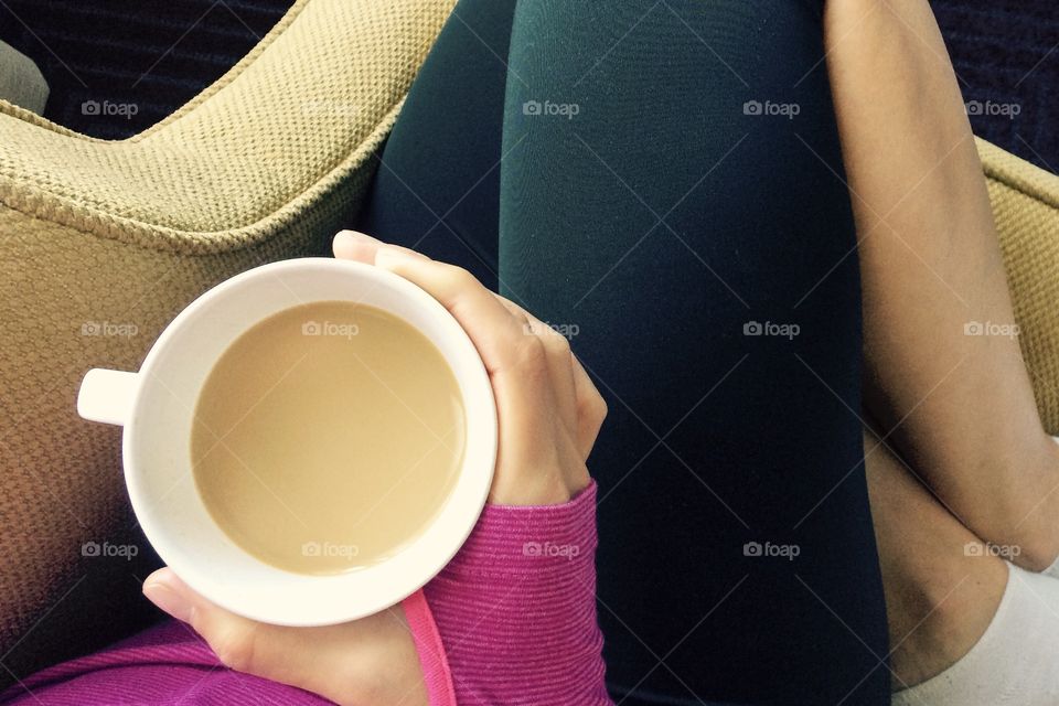 Cozy chair, coffee cup, cuddle spot close-up. Waking up in the morning can be difficult. But with a cozy chair and coffee cup, active females don’t mind the routine, pre or post workout.