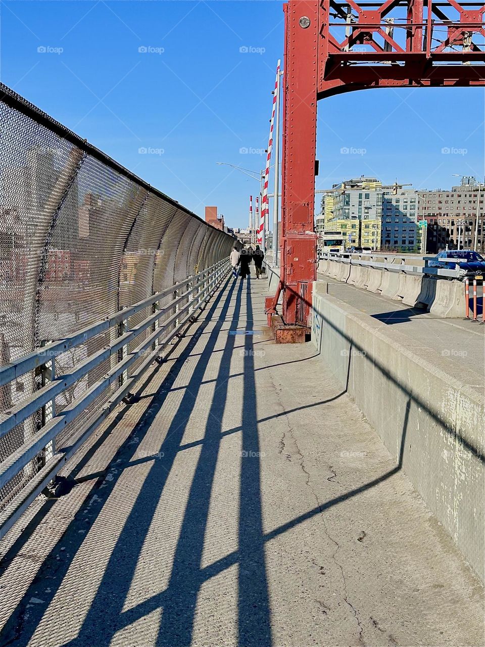 This is the pedestrian lane of the „Pulaski Bridge“ at „Newtown Creek“ that connects „Greenpoint“, Bklyn to LIC which is the direction we are currently walking in. The poignant shadow of the railing provides added guidance. 2024. Hypnotic Productions