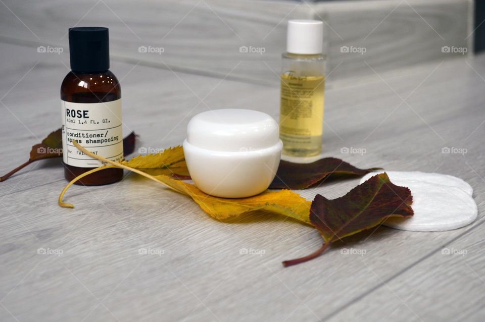 Jars with cream, shampoo and cosmetics on a background with autumn leaves