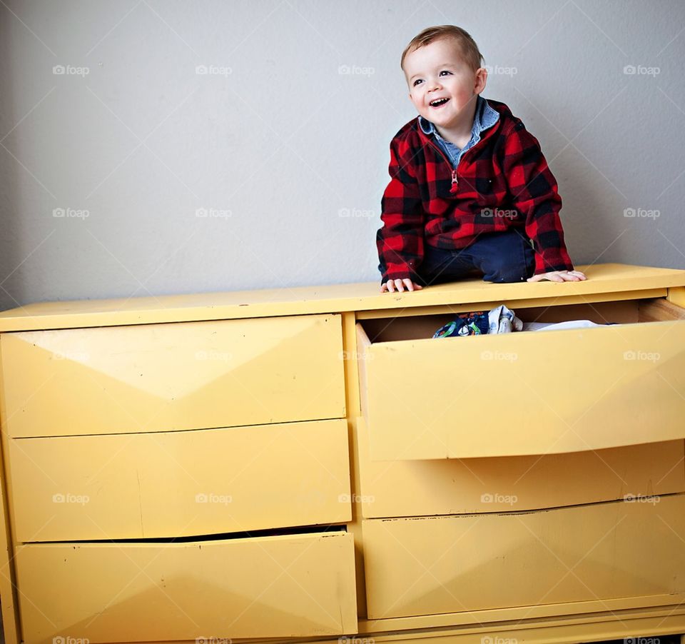 Toddler sitting on a yellow dresser 