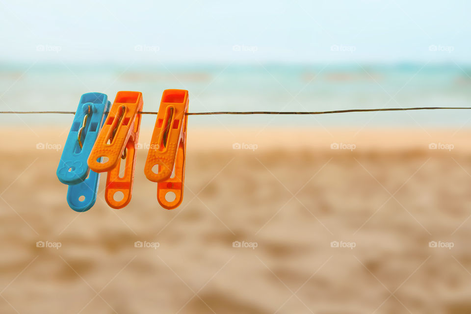 Concept colorful clothespin one blue two oranges pin with sling on nature sea and beach background