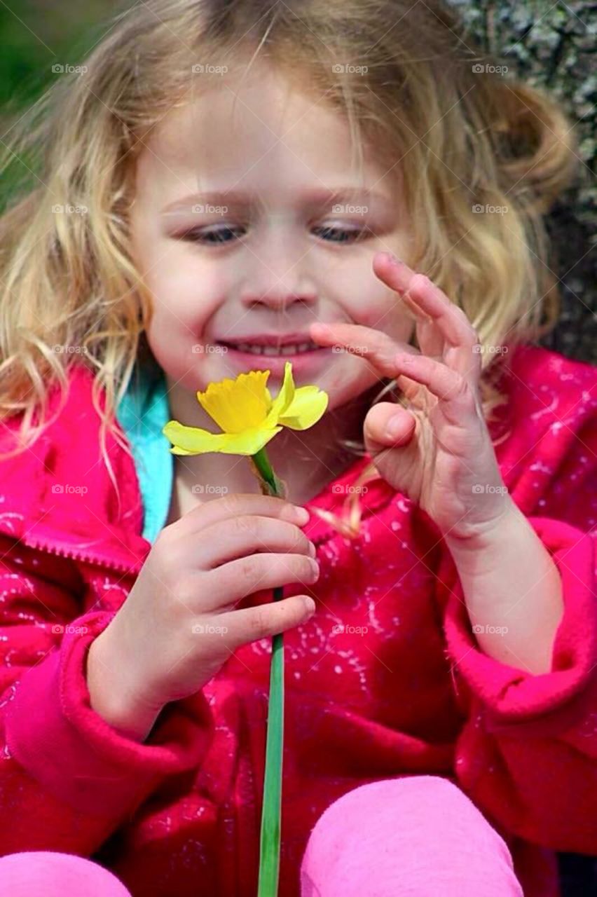 Sweet little girl admiring the beautiful flower she just picked. 