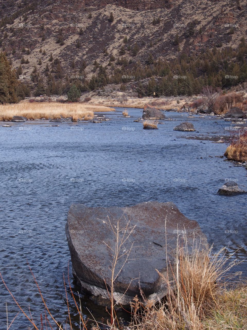 A large boulder on the banks of the Crooked River in a canyon in Central Oregon. 