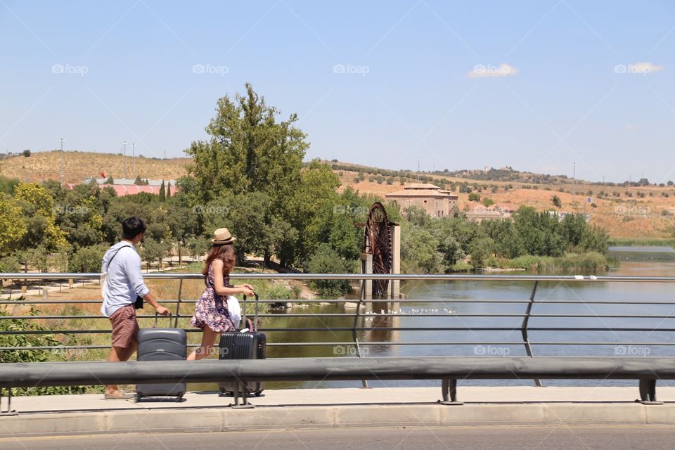 People walking over a bridge with their luggage