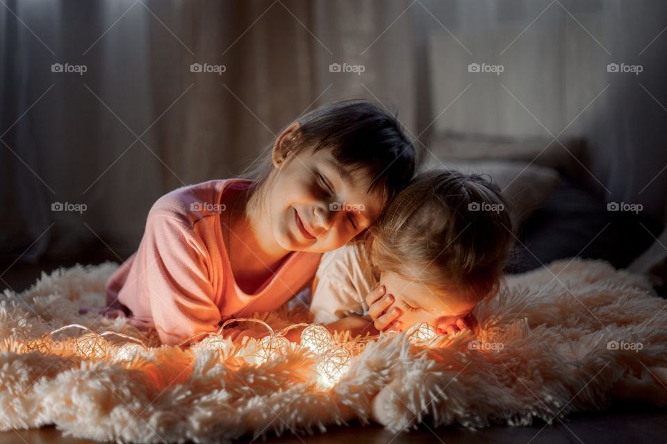 Little sisters reading a book at Christmas time 