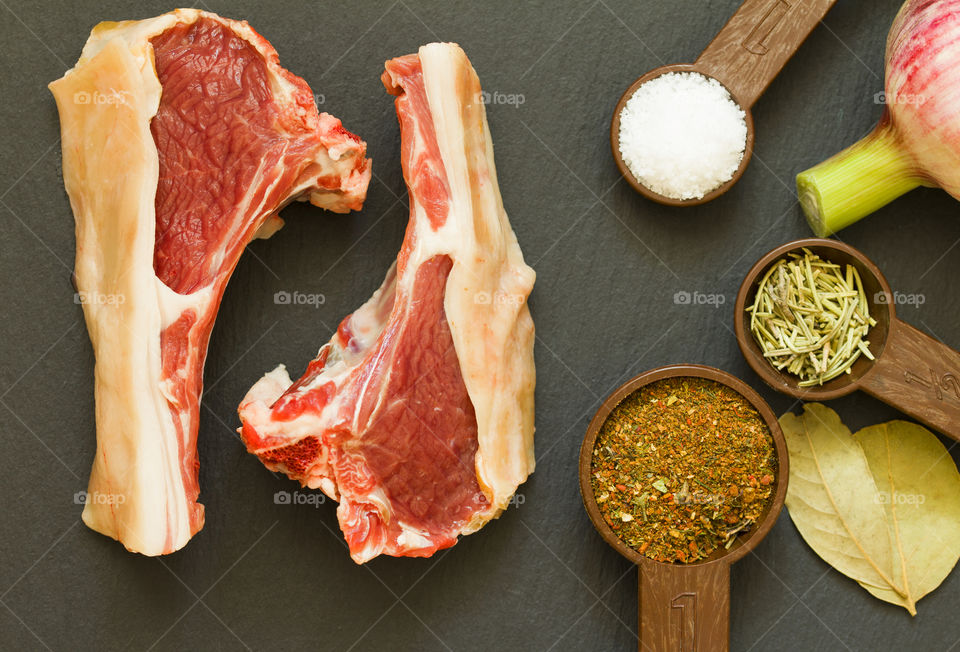 Raw mutton in the form of steaks on a stone board. there are spices on the board