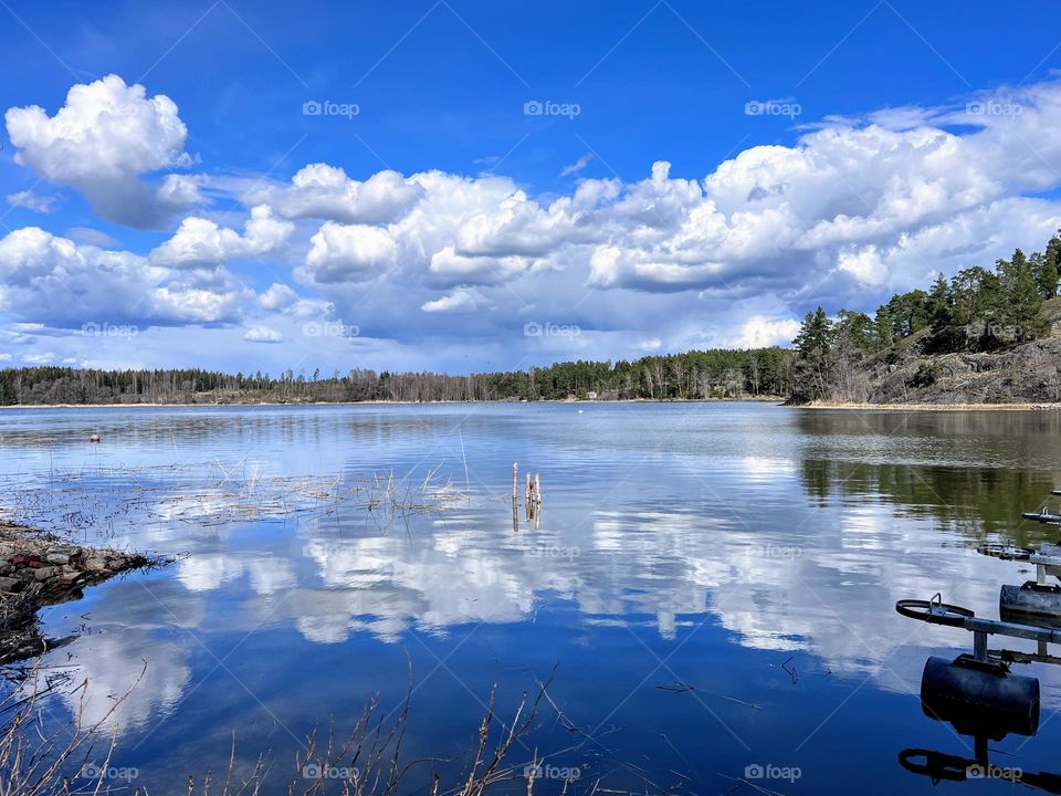 Beautiful landscape over the sea smooth surface with  fluffy white clouds reflecting in the water