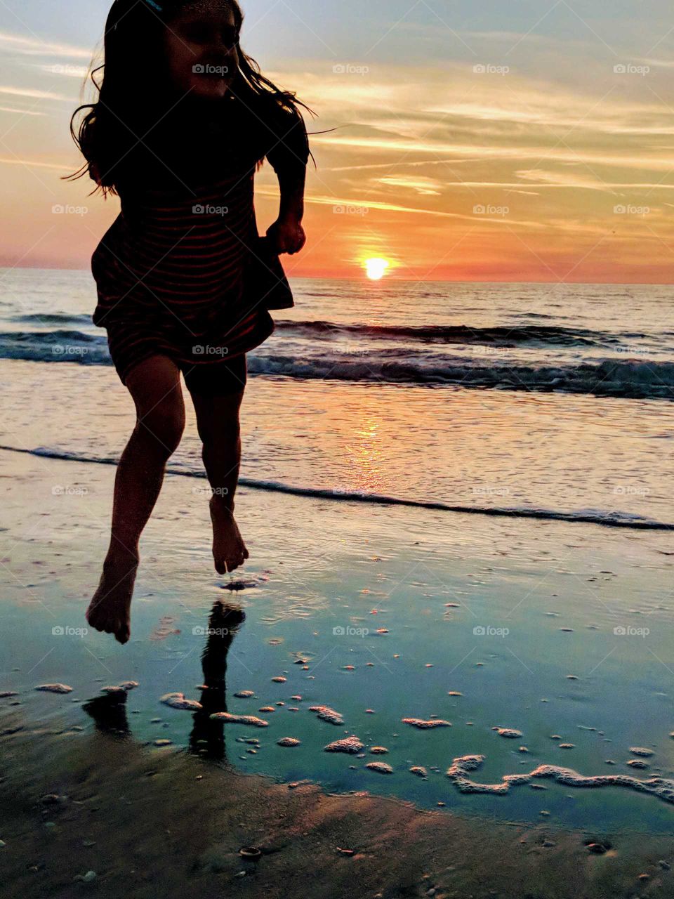 silhouette of little girl running on the beach