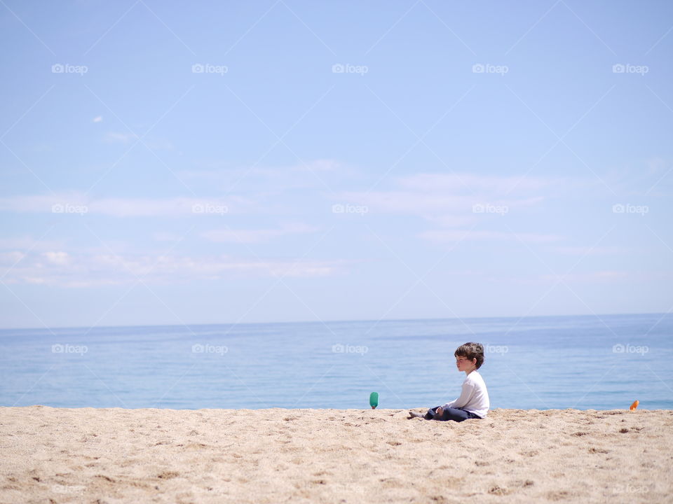 Little boy sitting on sand at beach