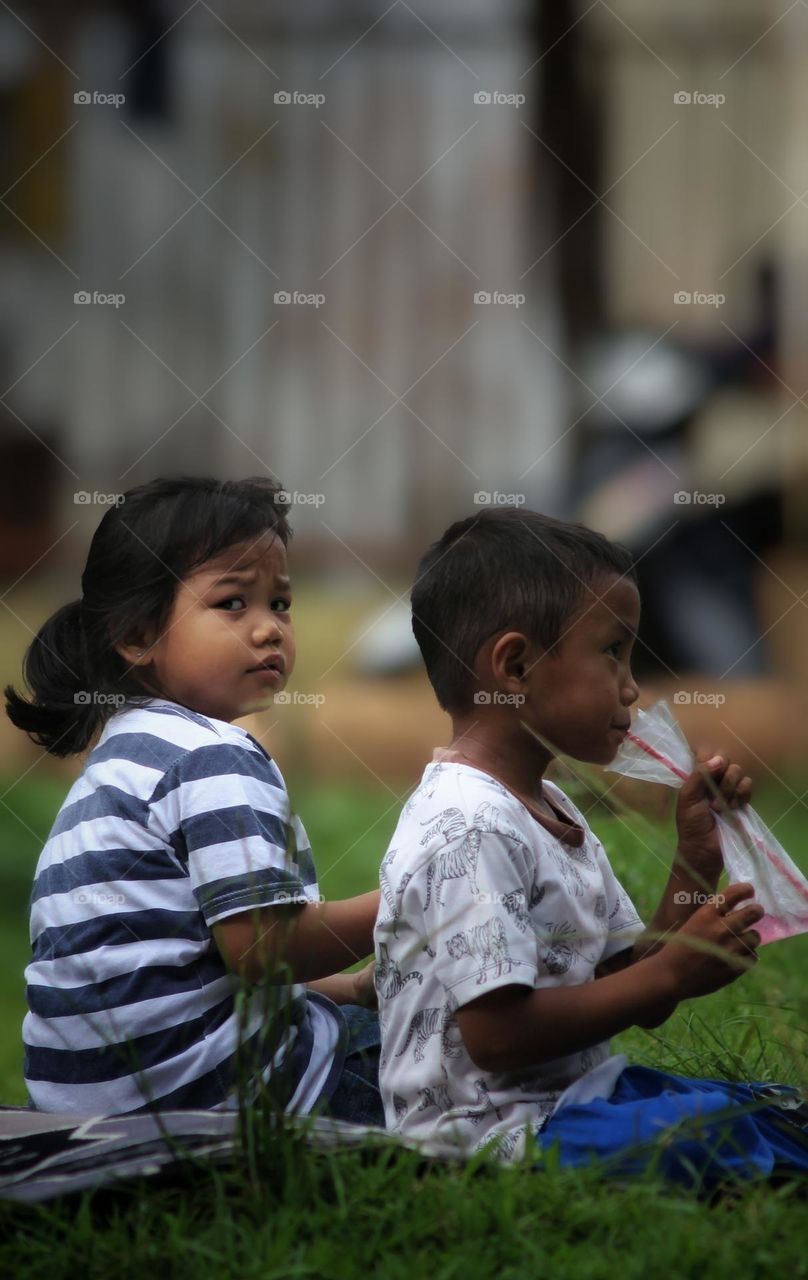 Two children are sitting in the field.