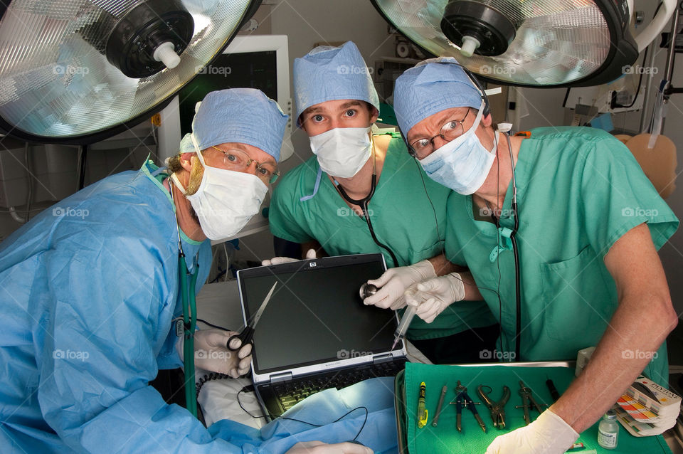 Three men operate on a computer on a operating table in an emergency