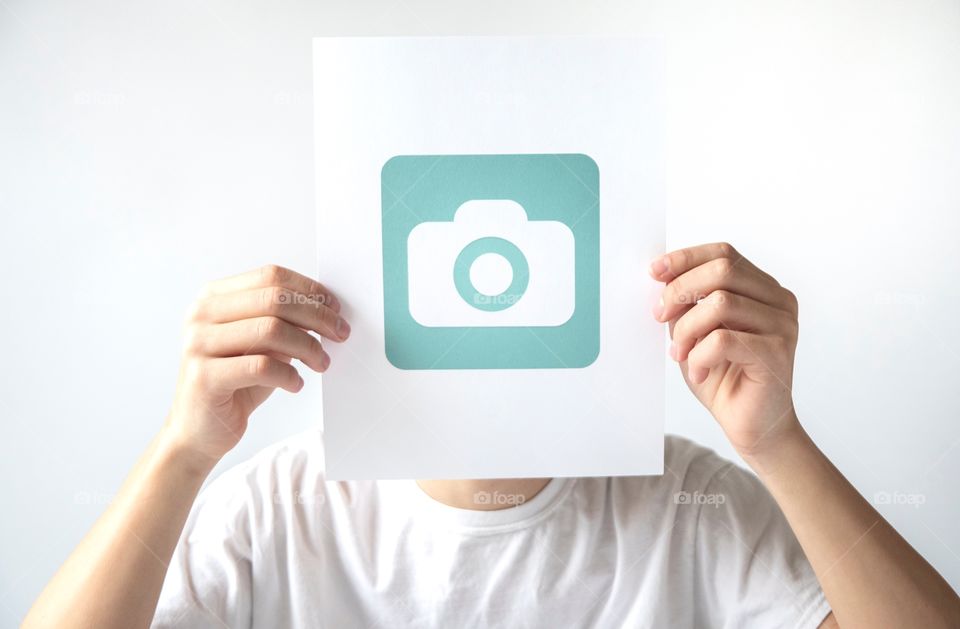 Young man holding a Foap logo in front of his face