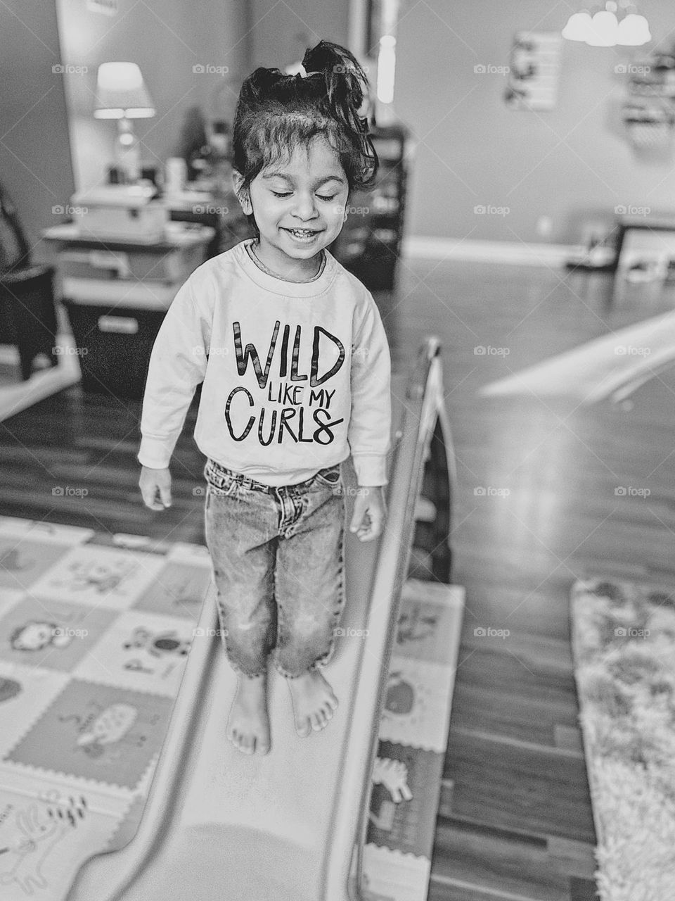 Child is running down slide with happiness, toddler smiling with happiness, toddler with eyes closed on a slide, wild like my curls little girl, cute toddler with cute saying on sweatshirt, child on a slide, playing indoors on a slide, sliding inside