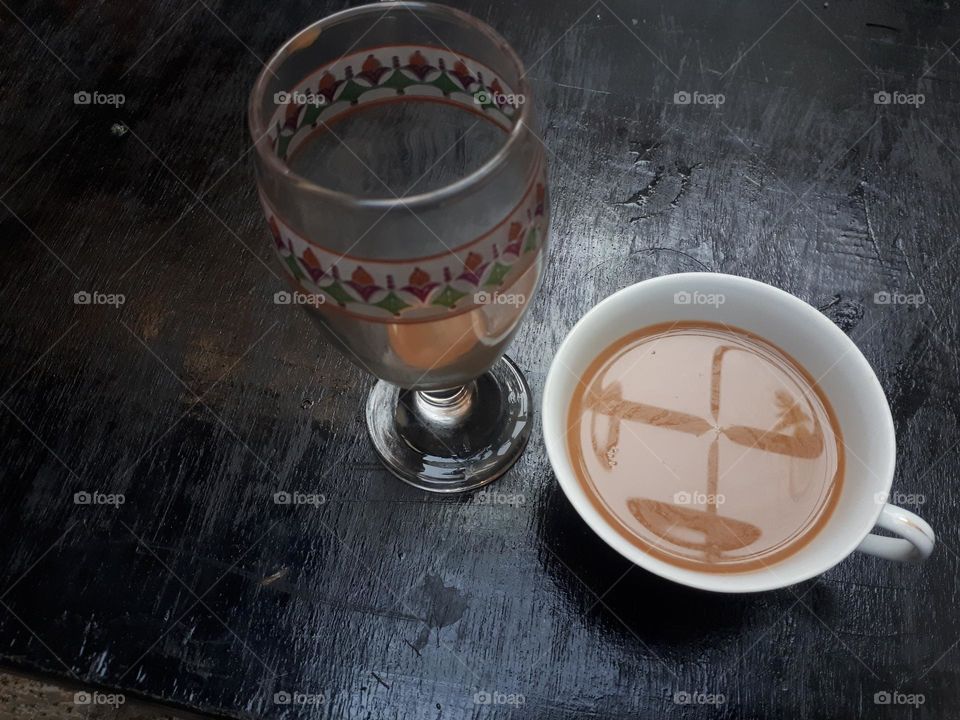 Artistic design of how to pour mocha coffee between 2 glasses on a black wooden table