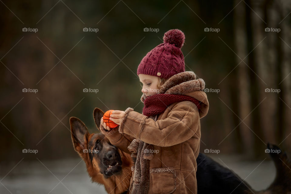 Little girl with German shepherd 6-th months puppy at early spring forest