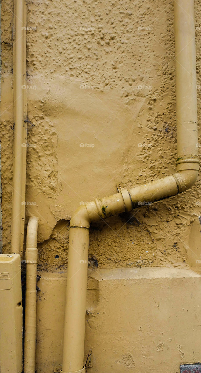 A mustard yellow wall & pipes