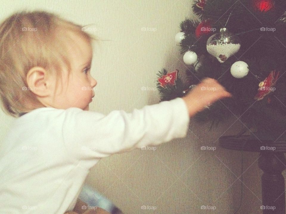 Baby trying to steel Christmas tree decoration 