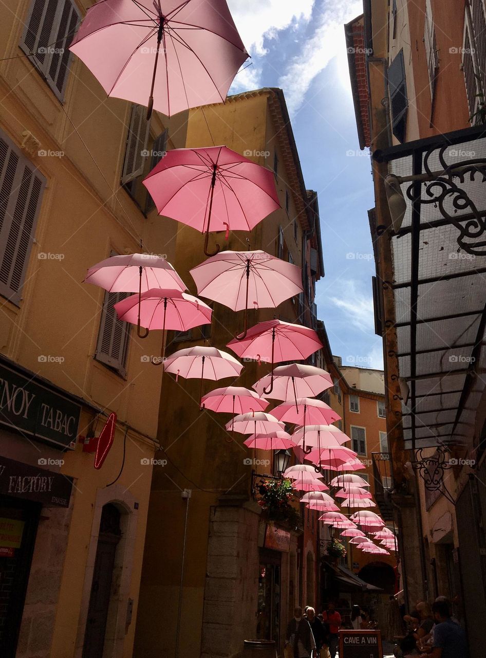 Pinky umbrellas as visual art in historic streets of Grasse city