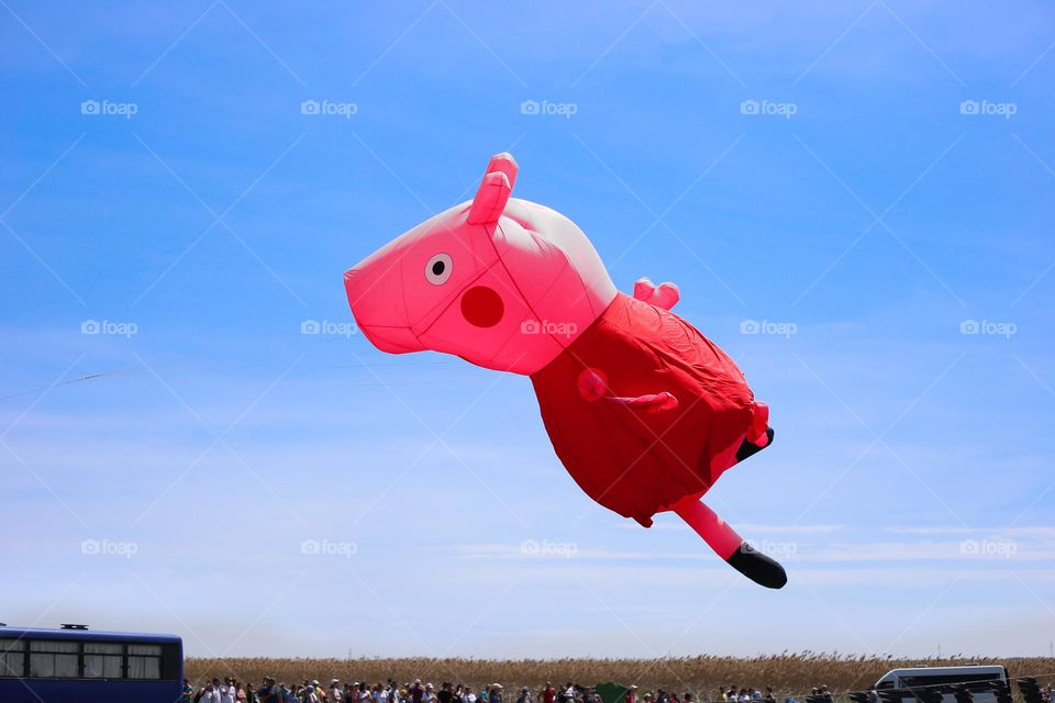 Pink Peppa pig kite flying in the blue sky 