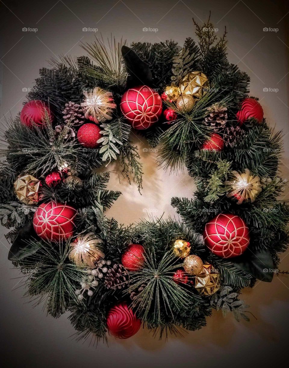 Christmas wreath with cones and red and gold ornaments on a front door