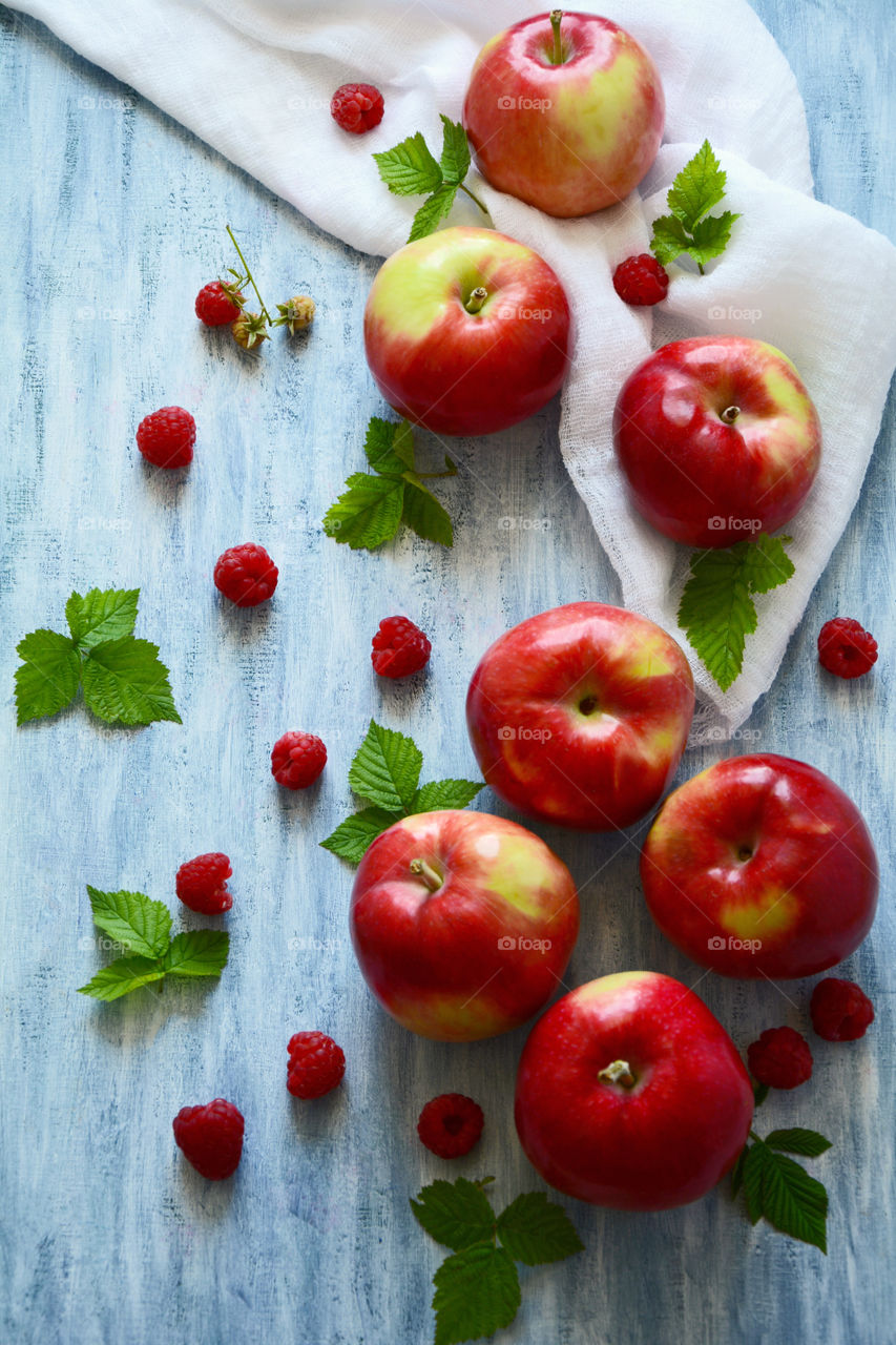 Apples and raspberries on blue wood