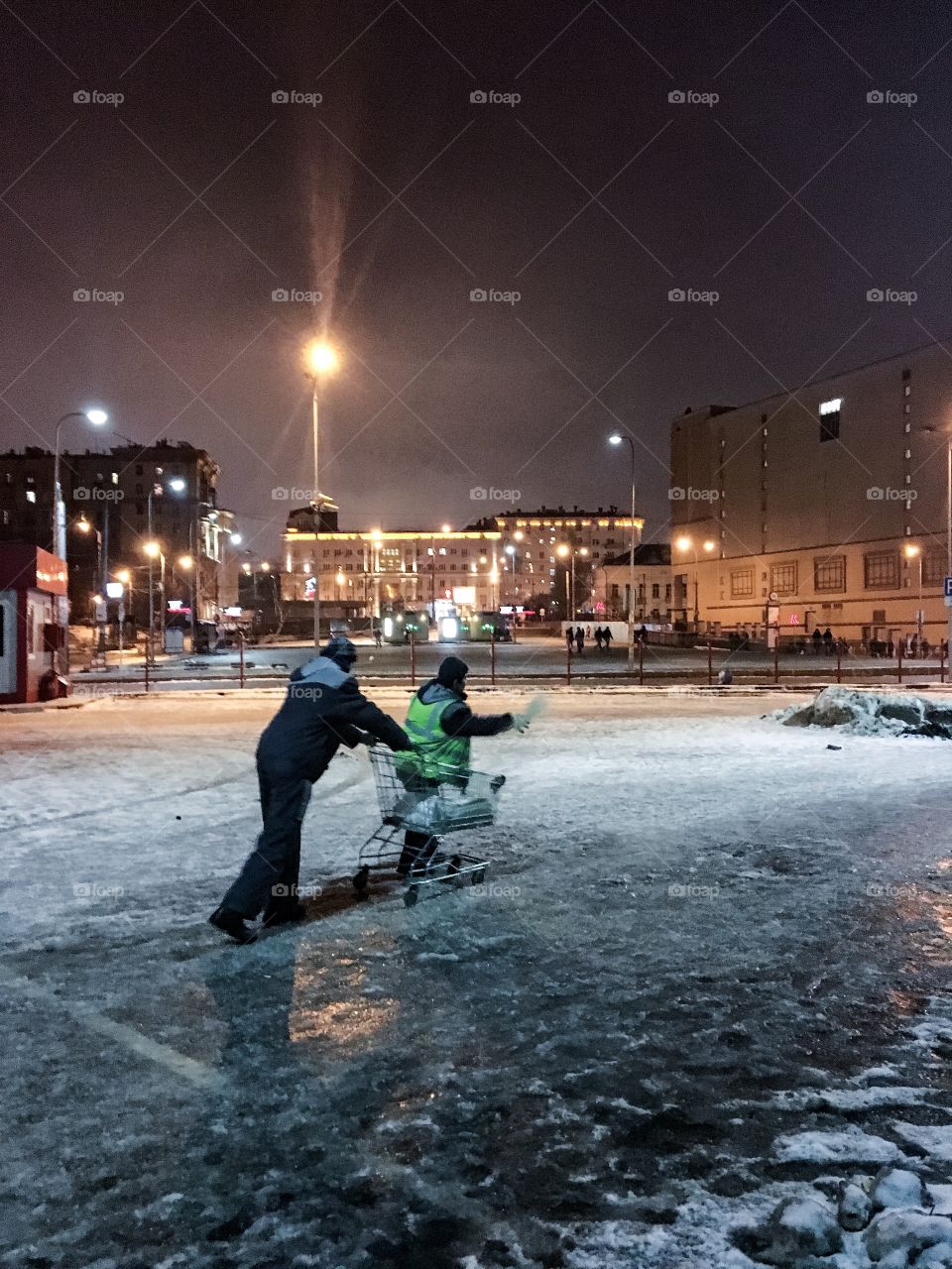 Two mans with supermarket on frozen ice square at night