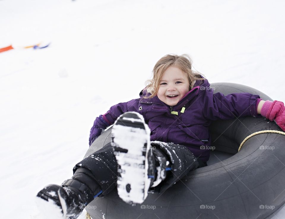 Little kid sledding down a hill in the snow 