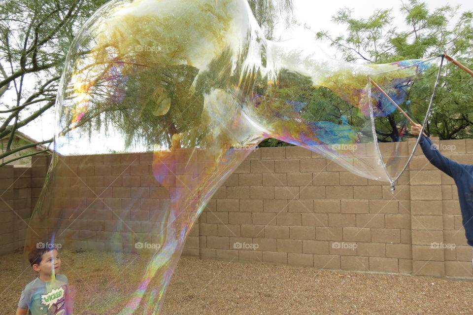 Little boy looking through a giant bubble.